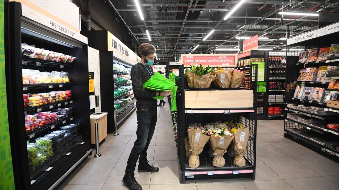 Ein Mitarbeiter des ersten Amazon-Fresh-Ladens in Europa räumt Einkaufstüten in ein Regal. 