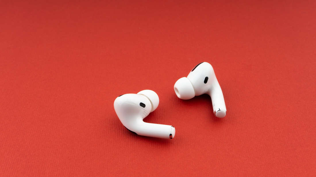 Apple AirPods Pro vor rotem Hintergrund.